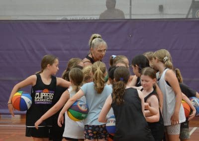 Suncoast Clippers Basketball Clippers Basketball camps young girls team with coach in a huddle in the middle of the court scaled